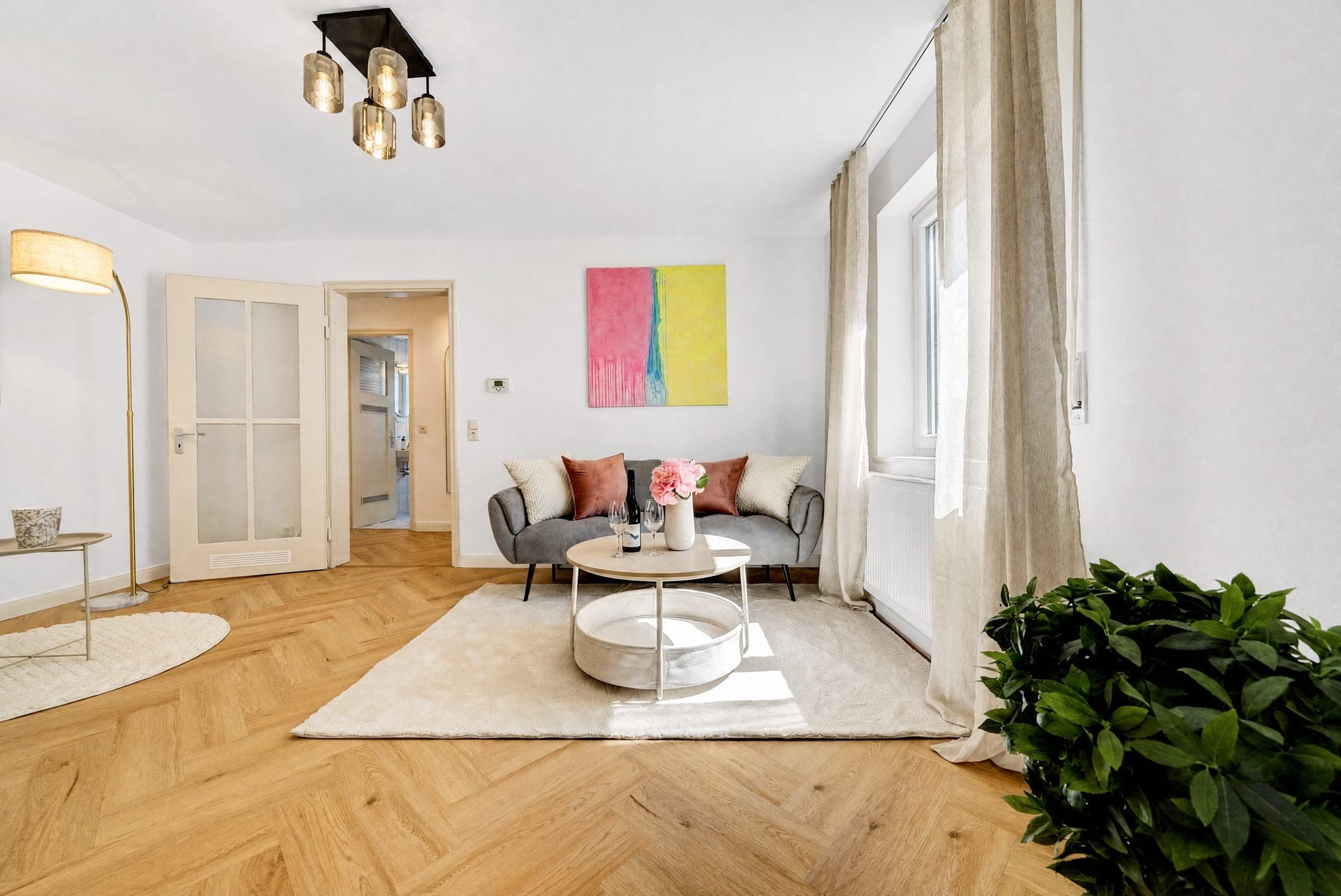 Wohnzimmer mit Sofa, bodenlangen Vorhängen und farbenfrohem Wandbild