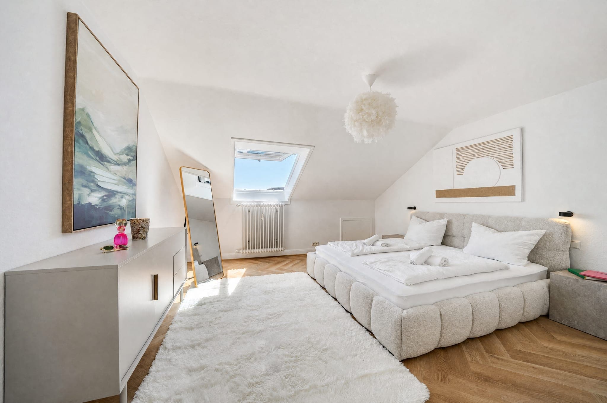 Dachgeschoss-Schlafzimmer mit Polsterbett unter der Schräge und Dachfenster