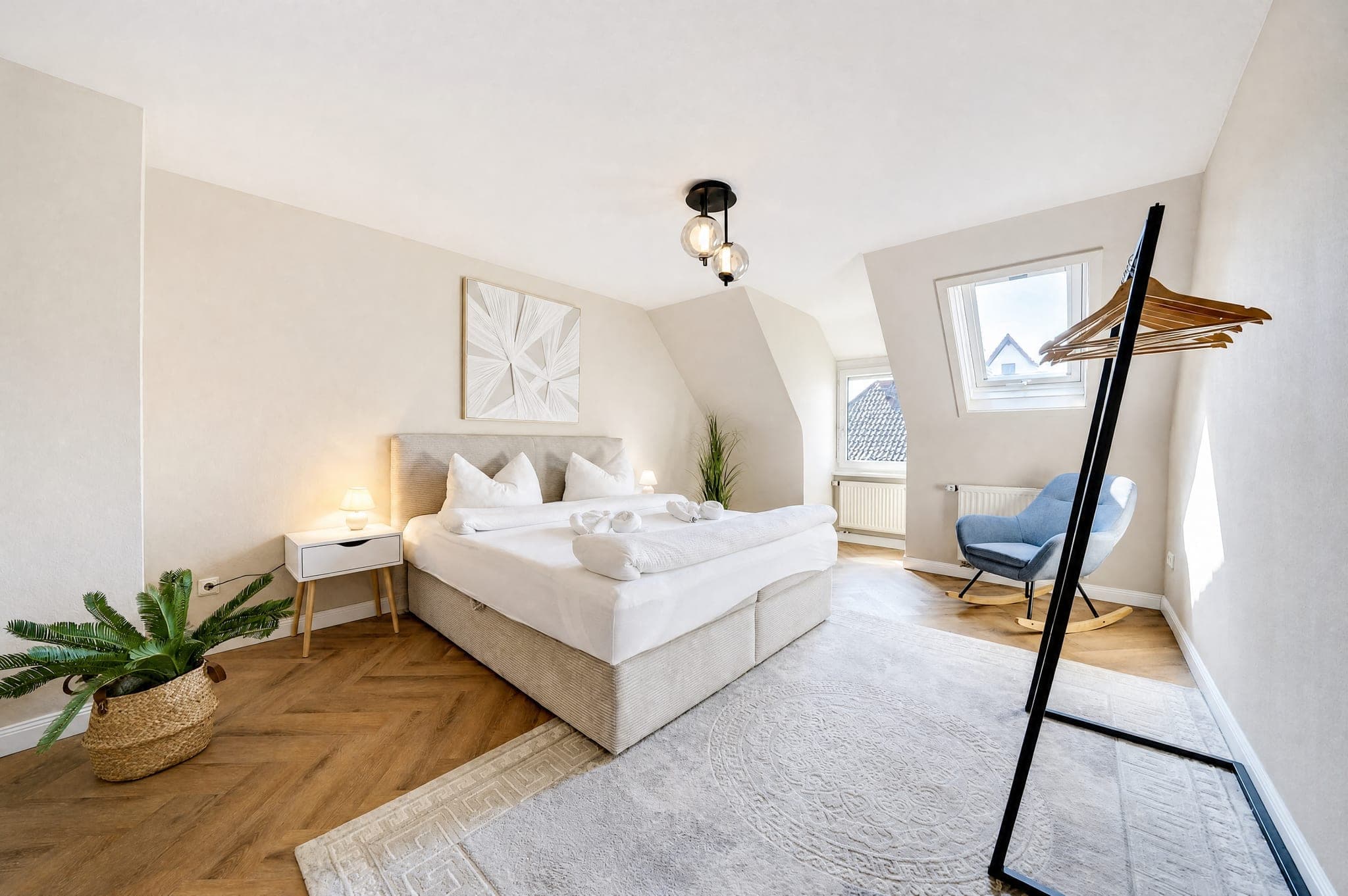 Schlafzimmer mit Boxspringbett und Sessel am Dachfenster auf Fischgrätparkett