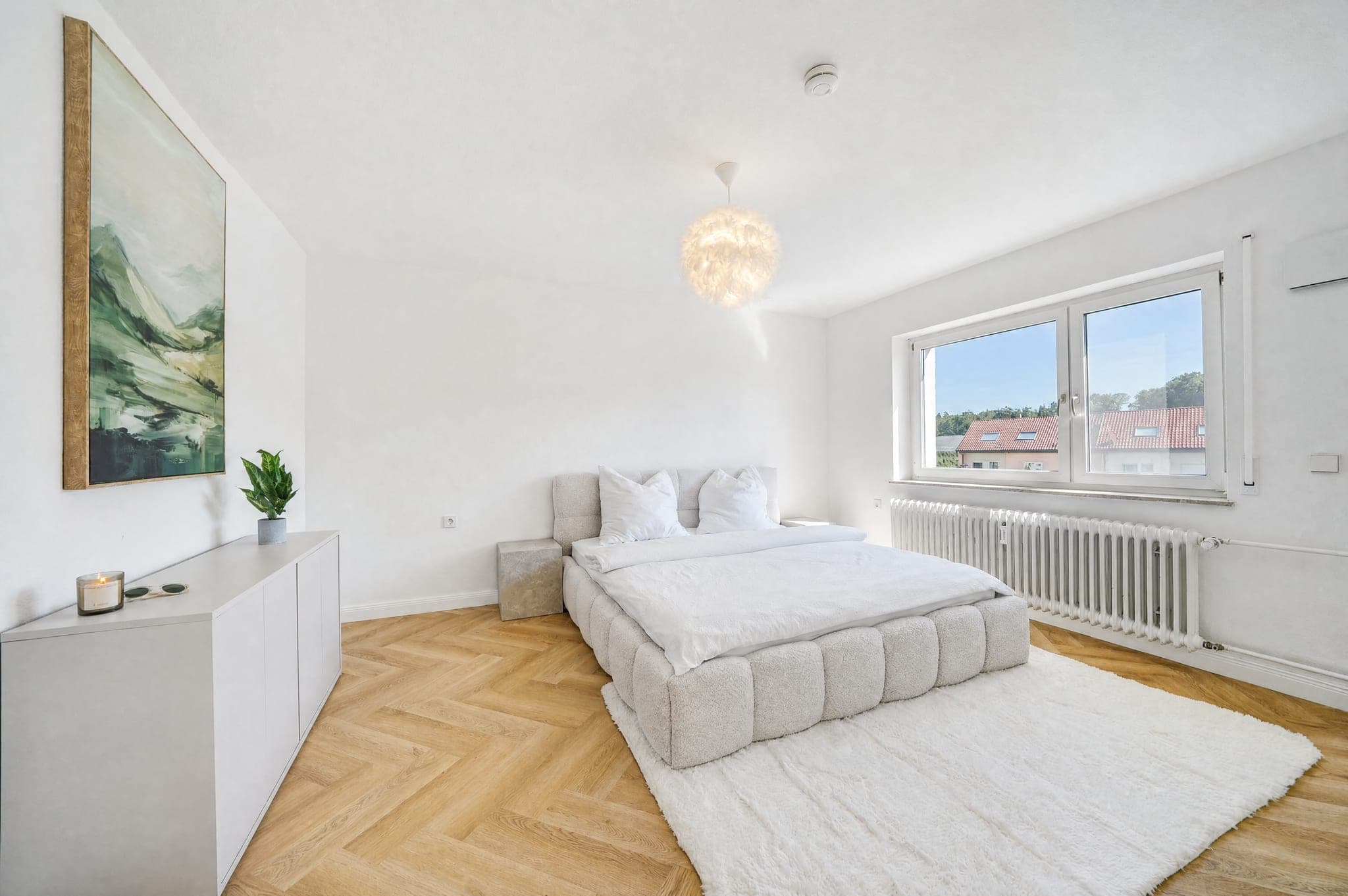 Schlafzimmer mit Polsterbett unter Dachschräge; das Fenster bleibt trotz Tageslicht durchgezeichnet