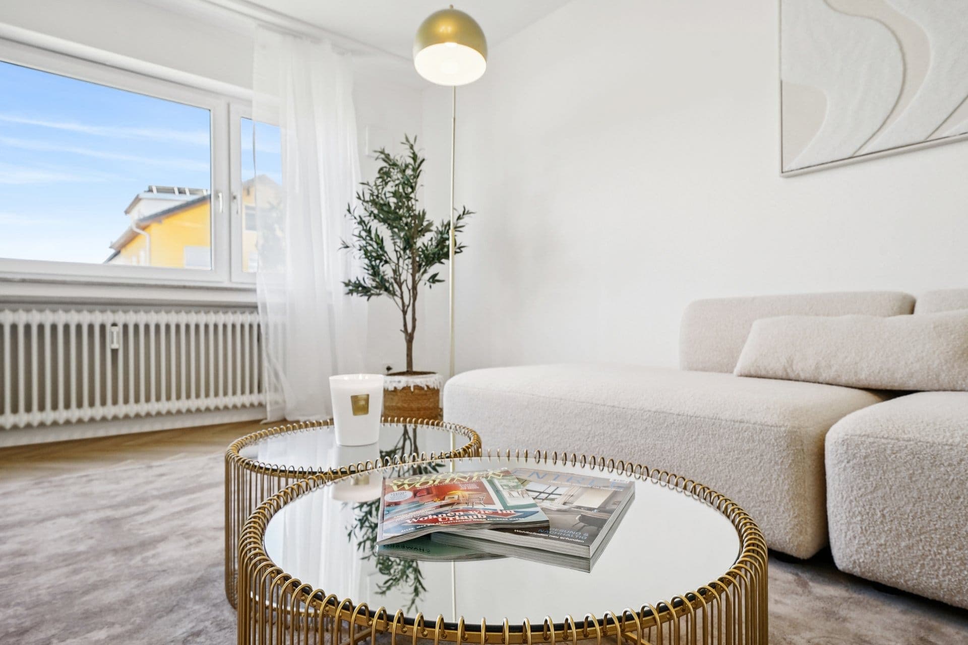 Wohnbereich mit Bouclé-Sofa und rundem Couchtisch vor dem Fenster