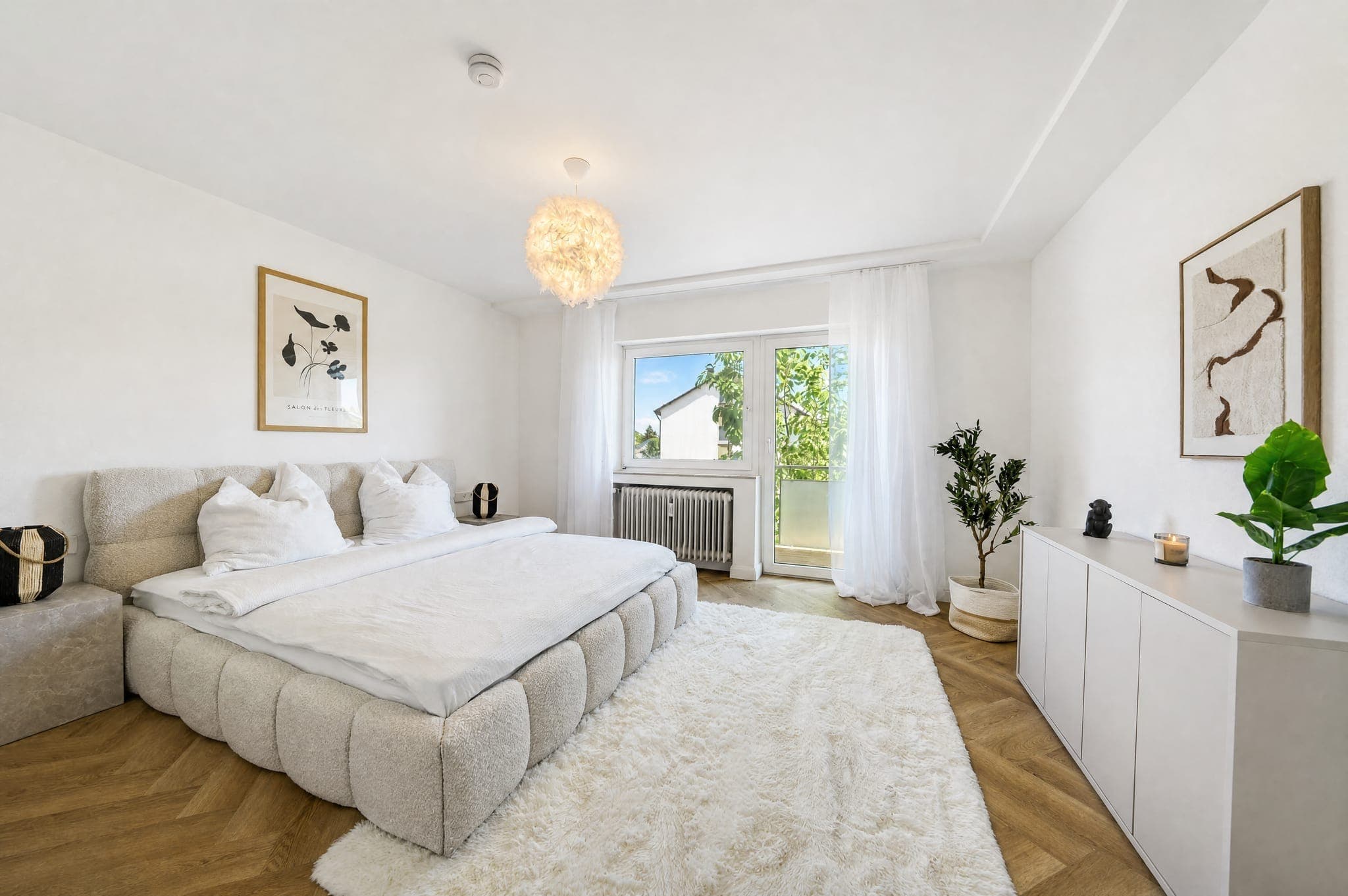 Schlafzimmer mit Polsterbett, Hochflorteppich und Balkontür hinter transparentem Vorhang