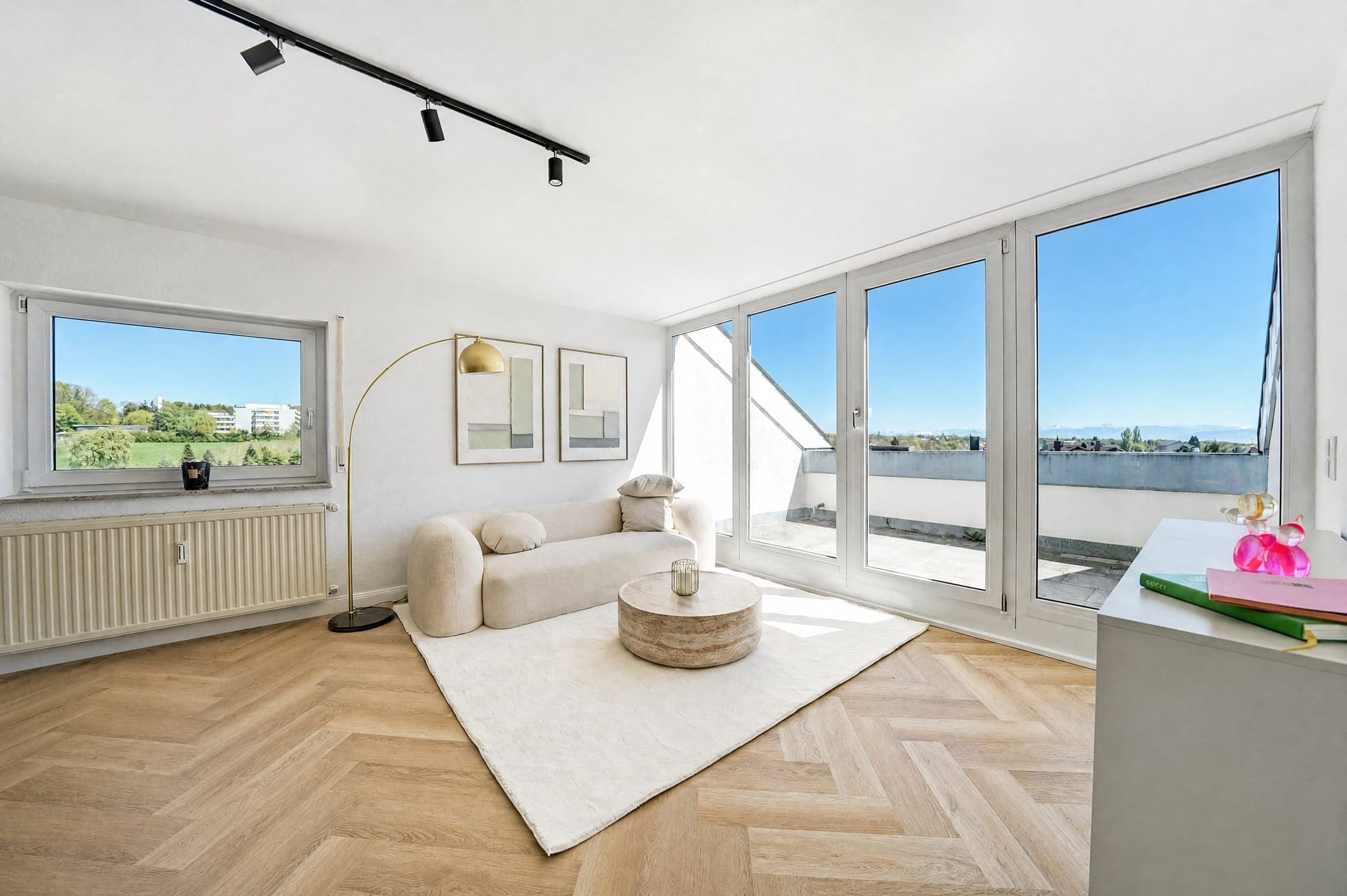 Wohnbereich mit Sofa zwischen zwei Fensterfronten und Blick über die Dächer