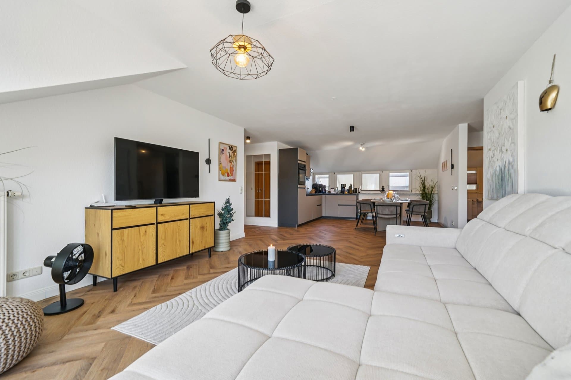 Offener Wohnbereich mit großem weißem Polstersofa und Durchblick bis in die Küche