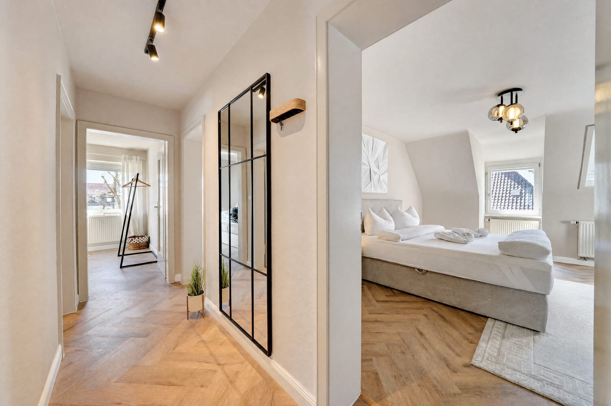 Blick durch eine schwarze Sprossentür in ein Dachgeschoss-Schlafzimmer mit Dachfenster