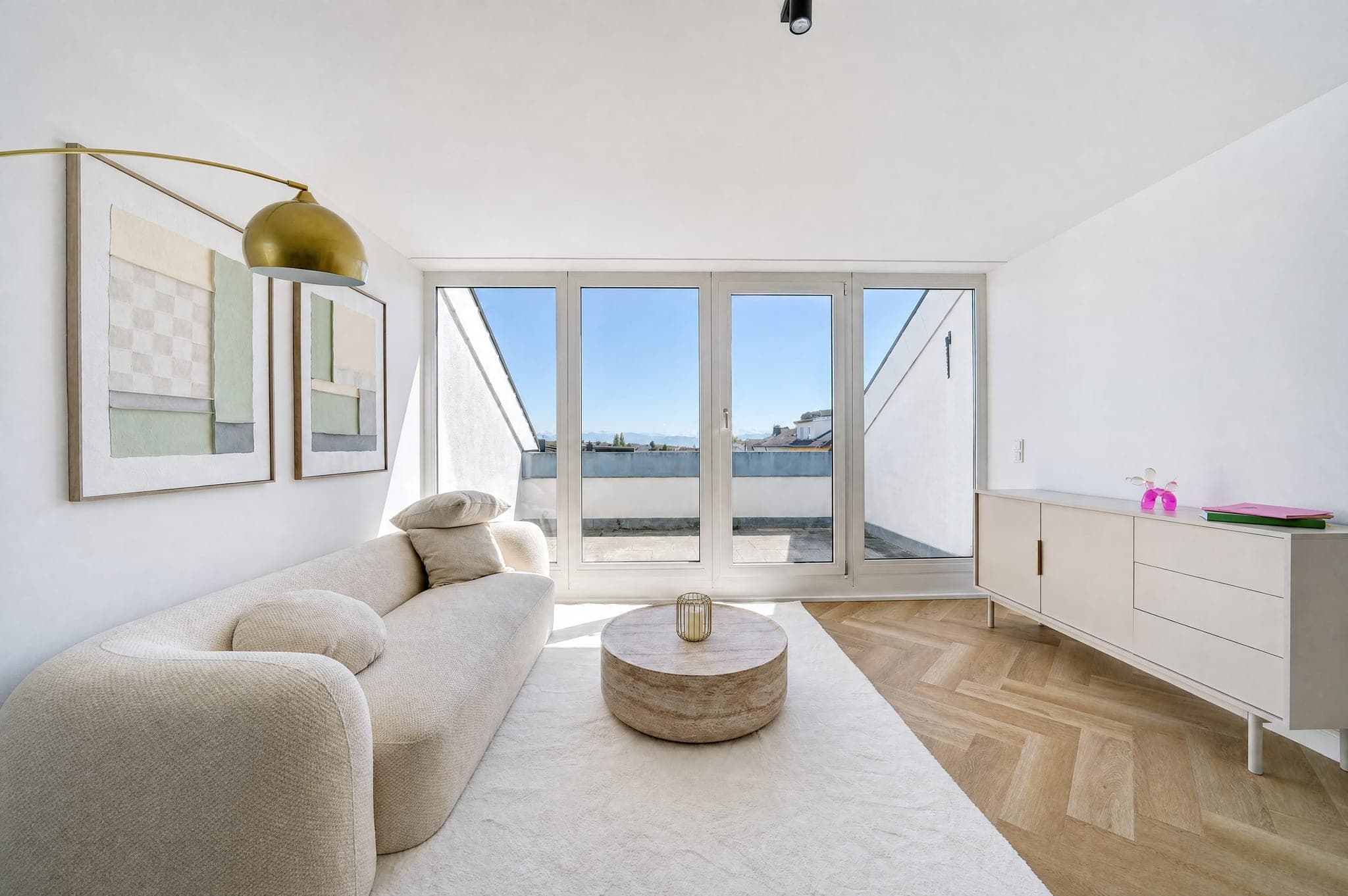Wohnbereich mit Rundsofa und Sideboard vor der Fensterfront zur Dachterrasse